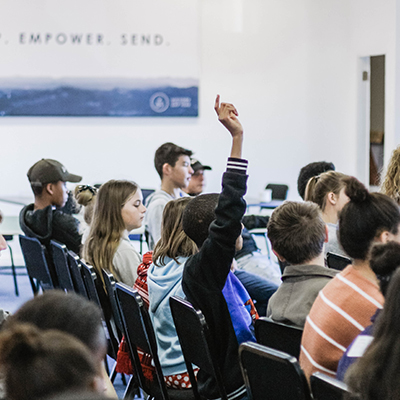 a classoom filled with students listening to a professor speak